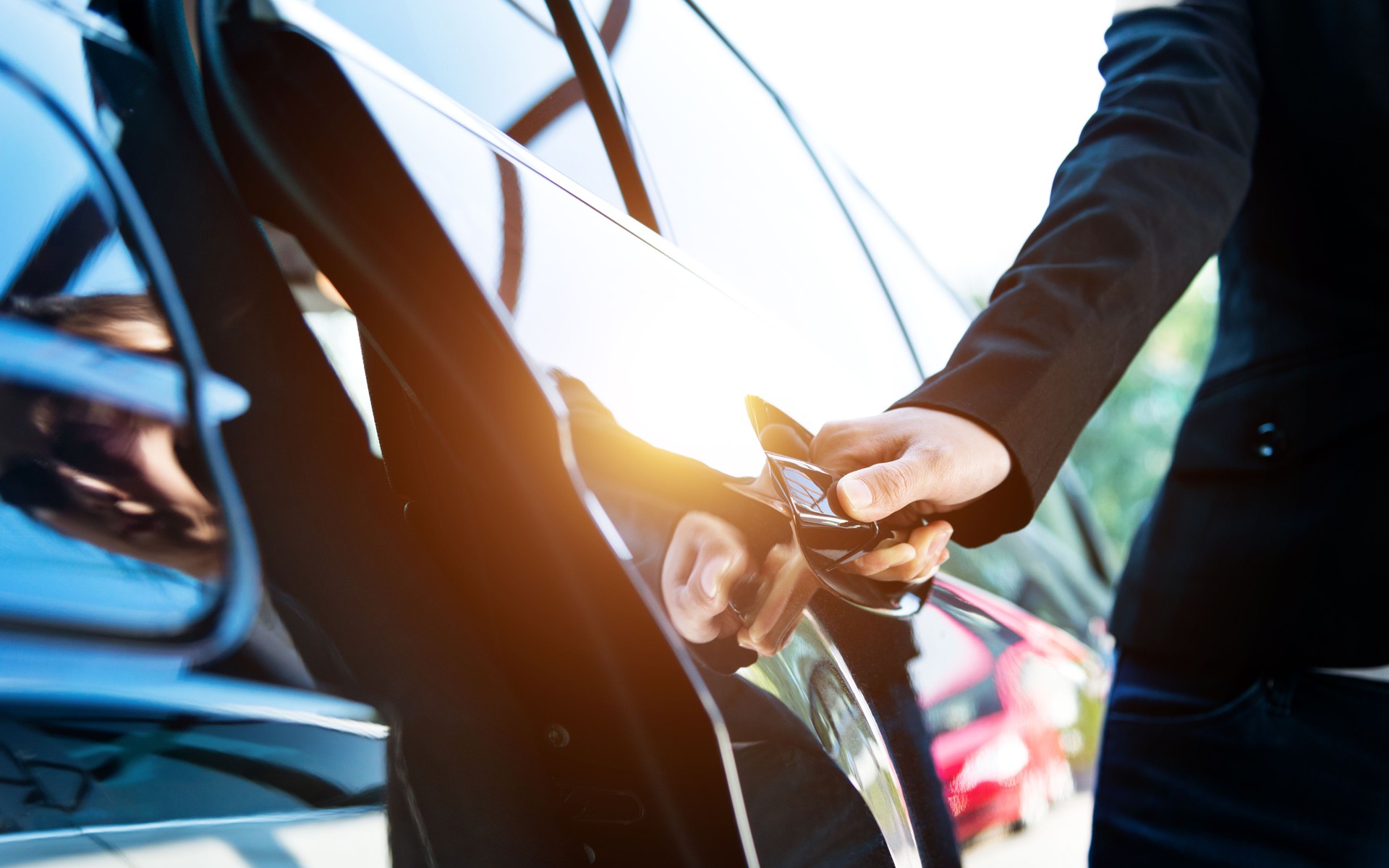 Female chauffeur opening a luxury car door
